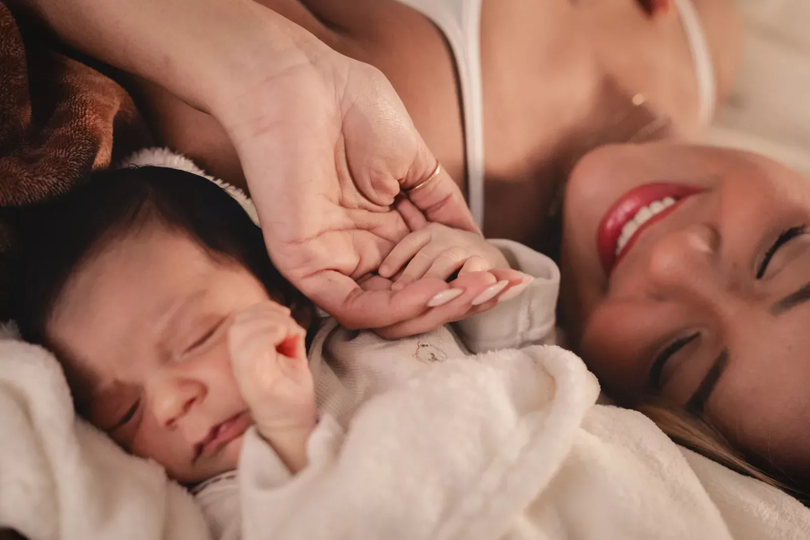 A mother and her newborn holding hands, capturing a tender moment of love.